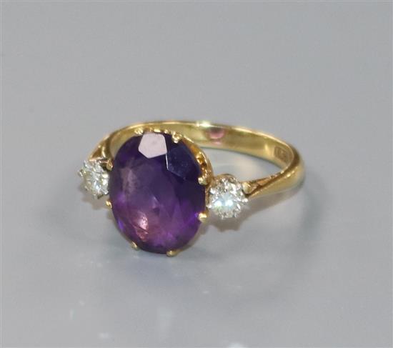 An 18ct gold amethyst and diamond three stone dress ring, size O.